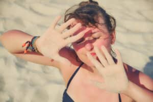Woman putting her hands in front of her face to block the sun from damaging her skin