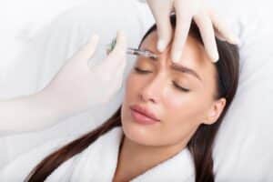 A pretty woman closes her eyes as her dermatologist administers her first Botox treatment