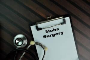 A doctor's clipboard with the words "Mohs surgery" prominently displayed, with a stethoscope seen in the background