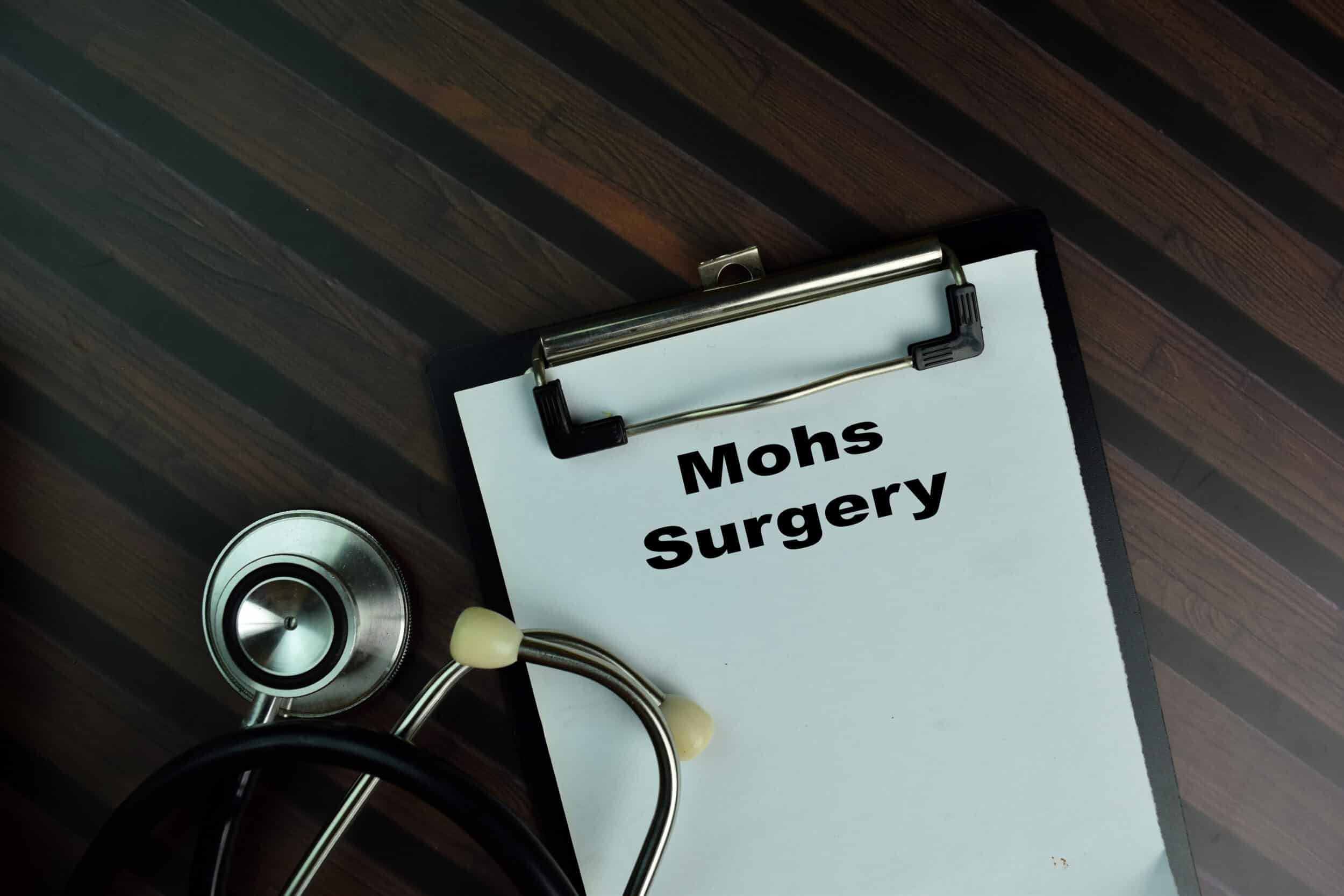 A doctor's clipboard with the words "Mohs surgery" displayed on it, with a stethoscope curled nearby