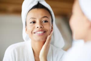 Woman looking in the mirror at her clear skin after SkinPen Microneedling in Lubbock, TX